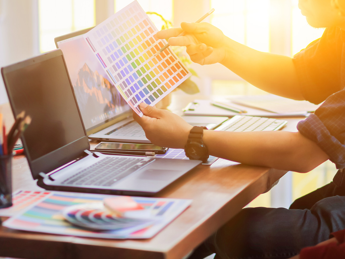 Person sitting at a desk in front of a laptop looking at colours